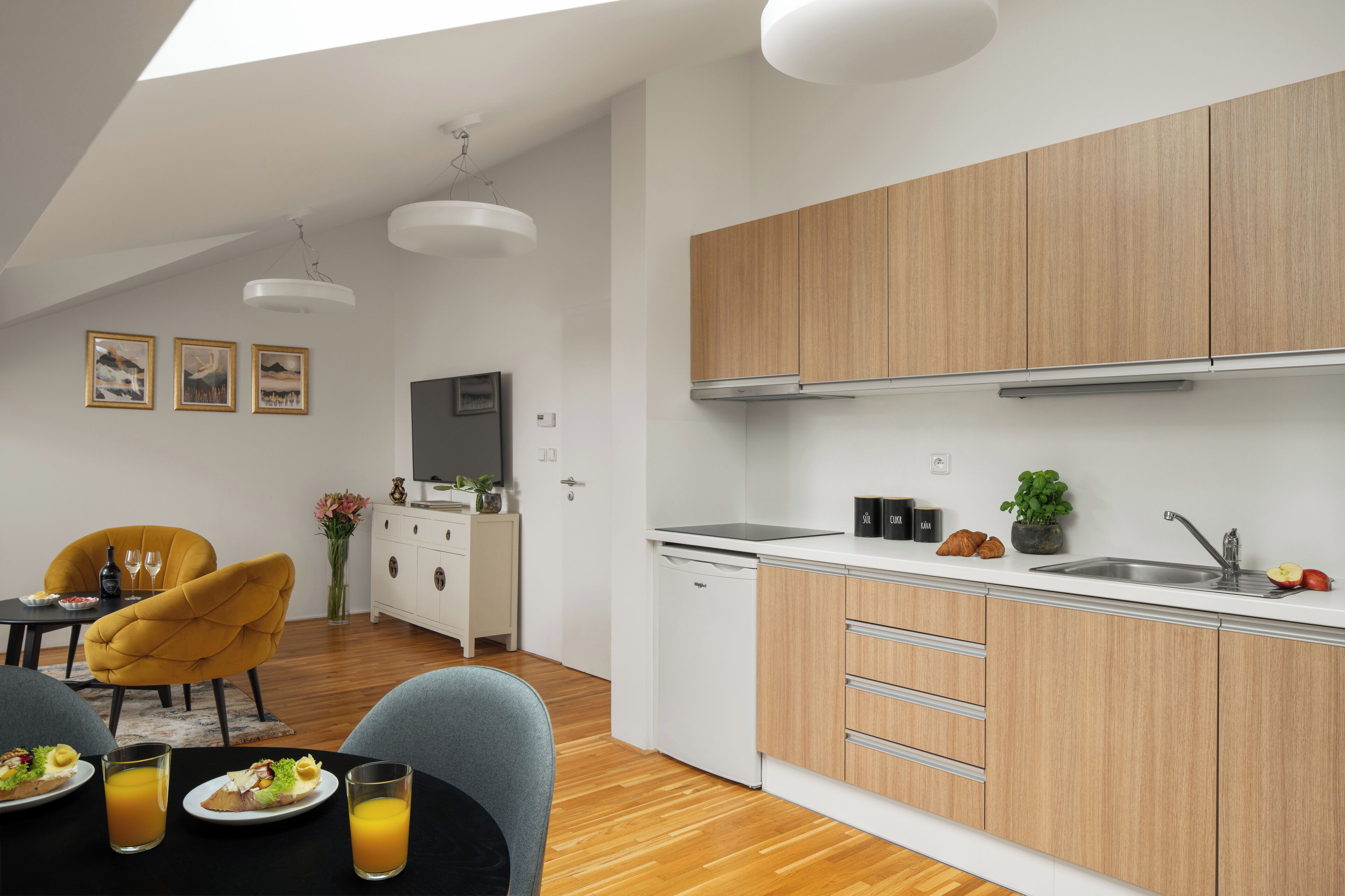 A modern kitchen with wooden cabinets, a sink, and a dining area with a table and chairs.