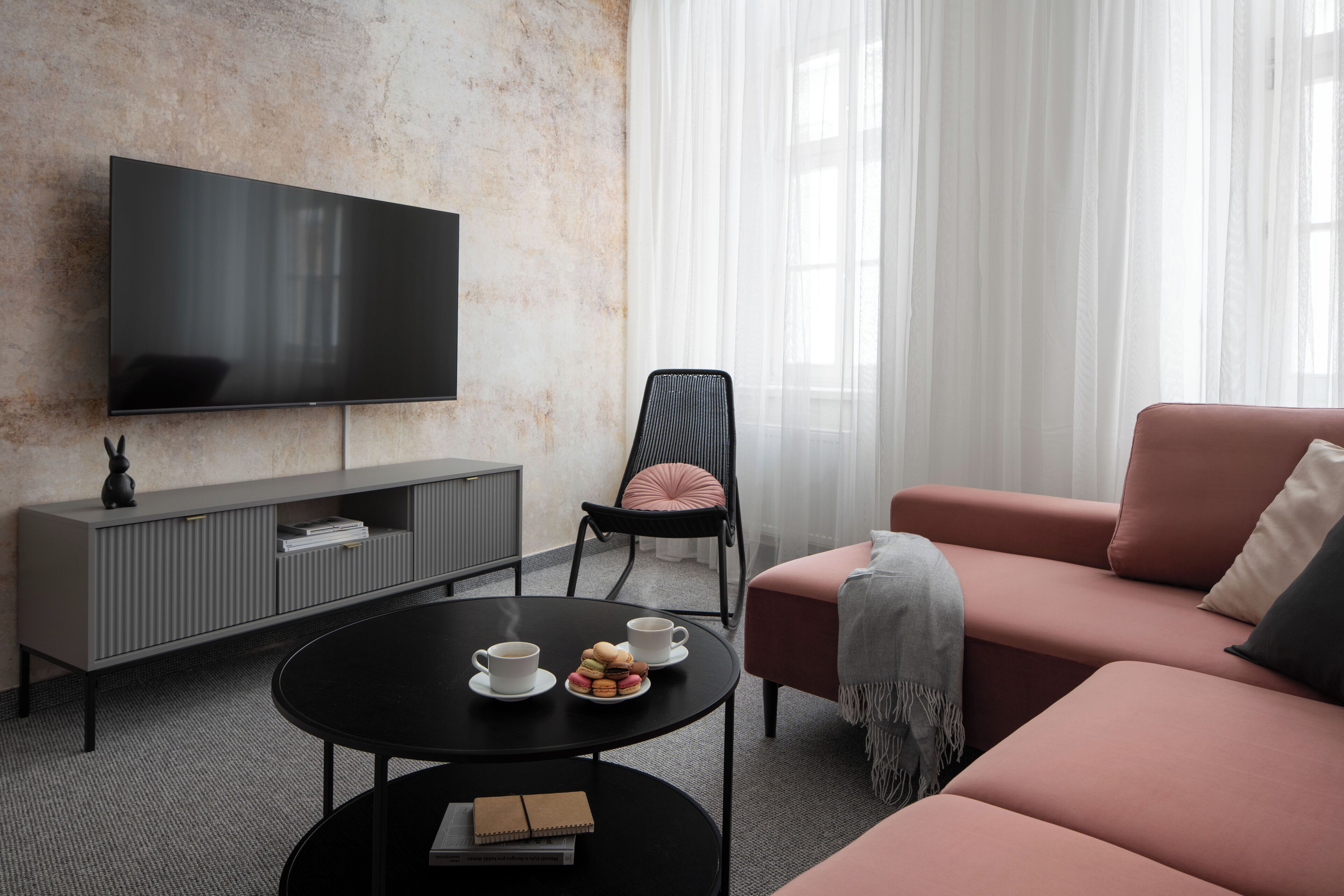 A modern living room with a flat-screen TV, a sofa, a chair, a coffee table, and a bookshelf.