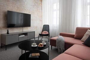 Una sala de estar moderna con un televisor de pantalla plana, un sofá, una silla, una mesita de centro y una estantería.