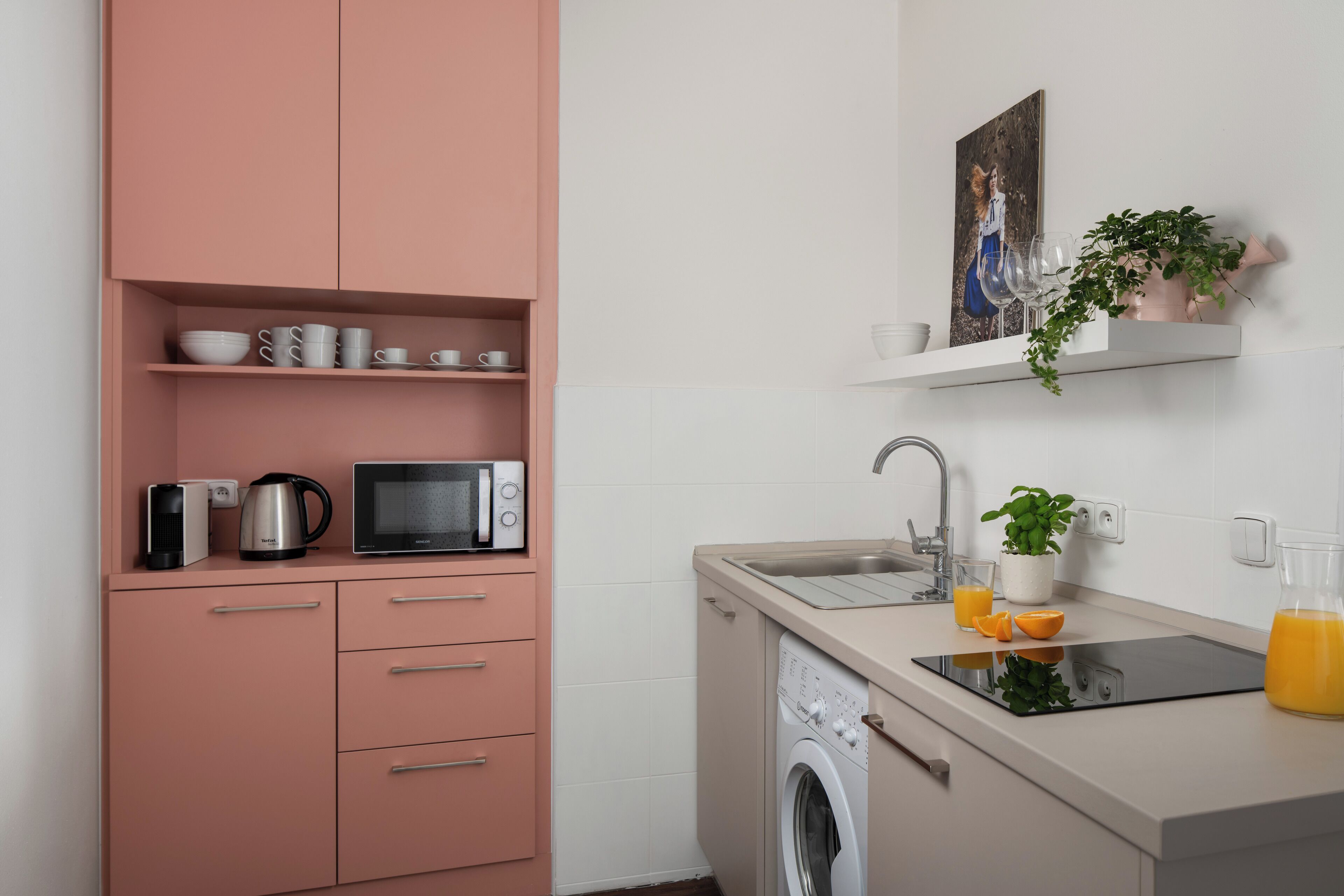 A modern kitchen with a washing machine, microwave, and coffee maker on the countertop.