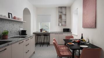 Una cocina moderna con comedor, que cuenta con una encimera de mármol, una mesa de comedor negra y sillas rosadas.