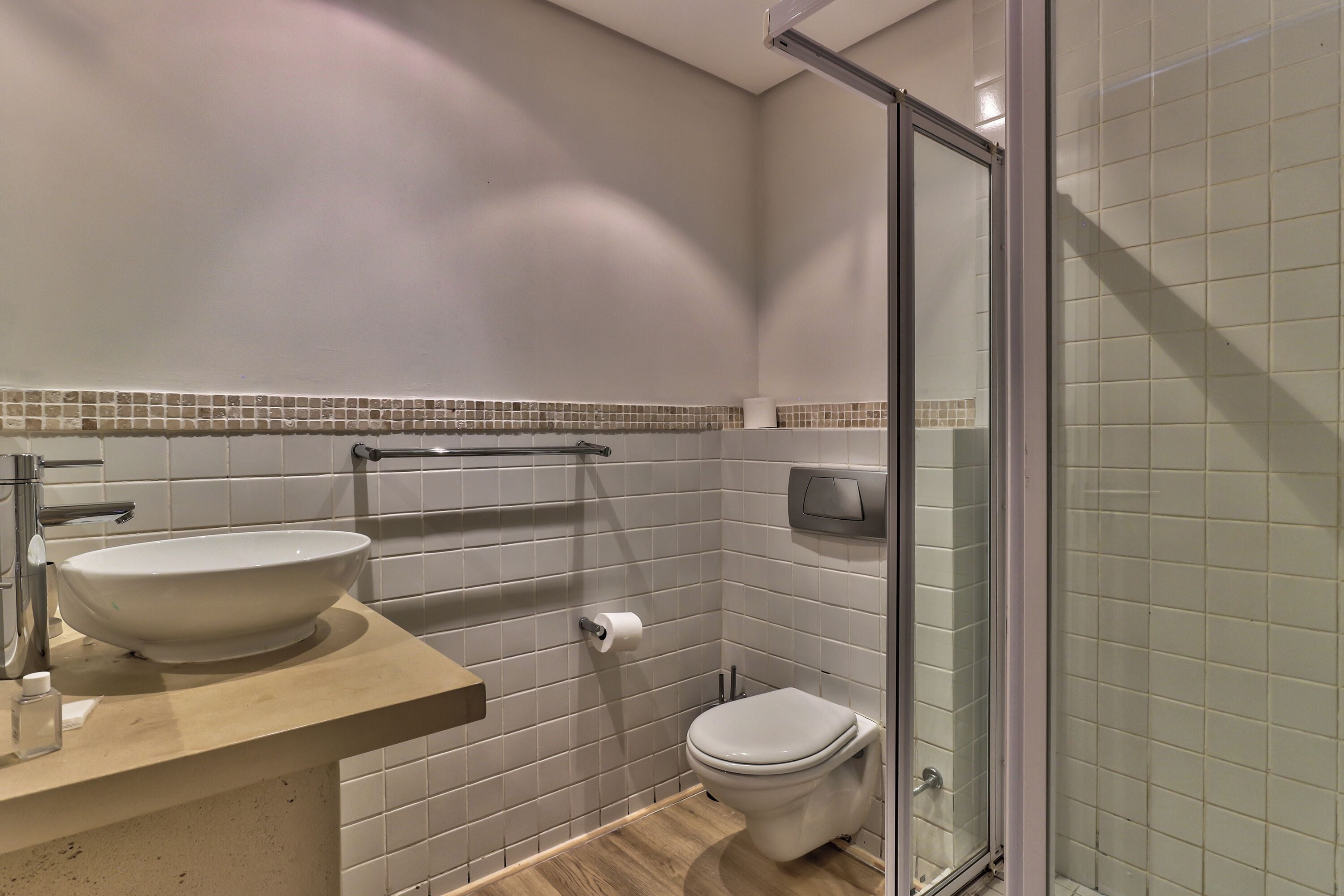 A bathroom with a large white sink, a toilet, and a glass shower enclosure.
