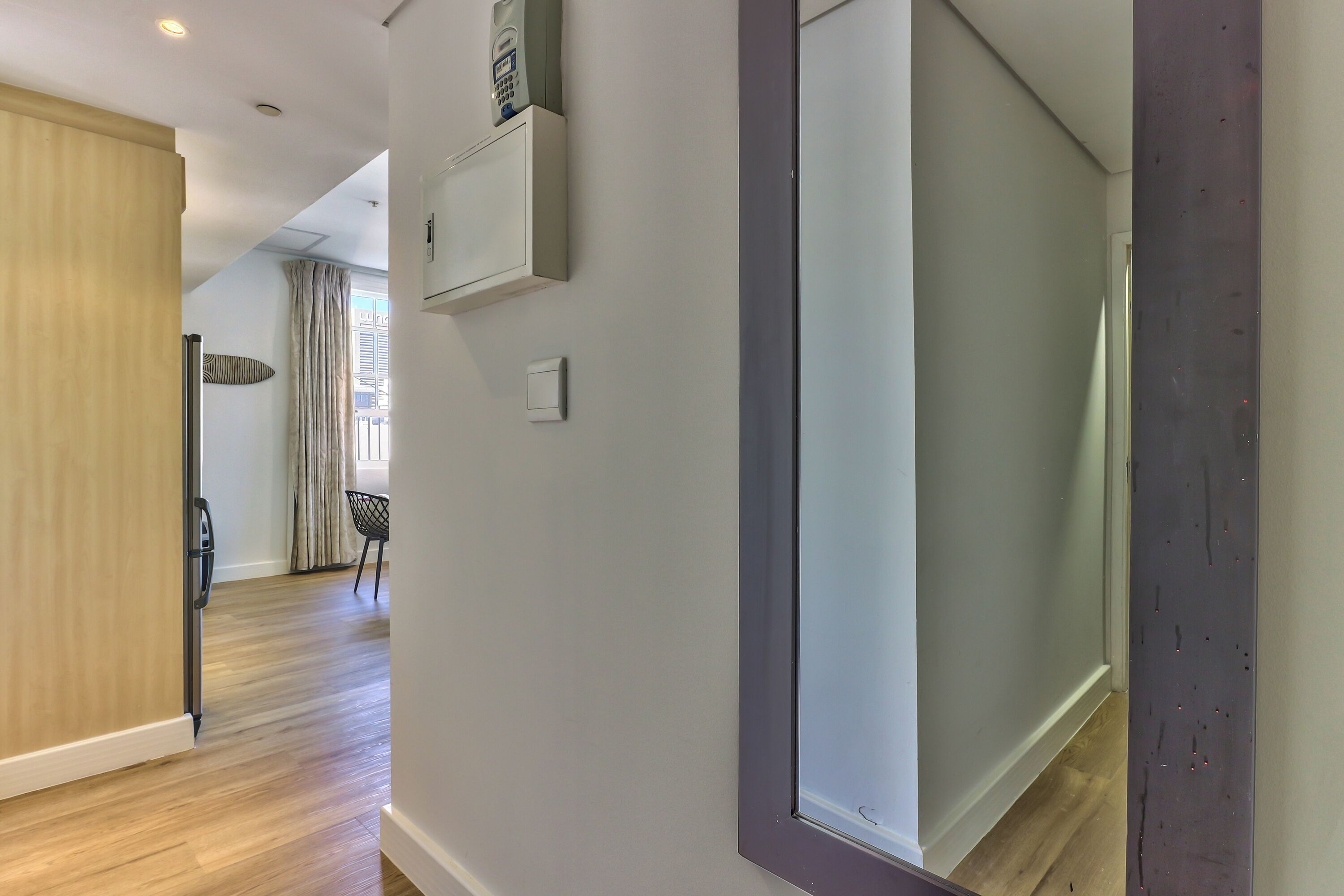 A modern interior with a wooden floor, a sliding door, a wall-mounted air conditioning unit, and a visible light switch.