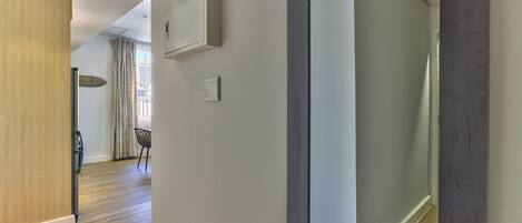 A modern interior with a wooden floor, a sliding door, a wall-mounted air conditioning unit, and a visible light switch.