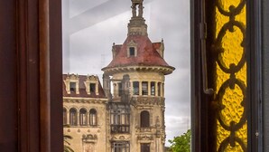 A view through a window with a decorative frame, revealing a historic building with a red roof and multiple windows. - Hotel Boutique Loriente (Ribadeo)