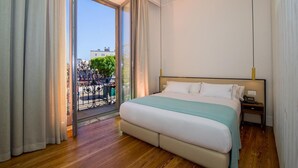 A bedroom with a large bed, a nightstand, and a view of the city through a glass door. - Hotel Boutique Loriente (Ribadeo)