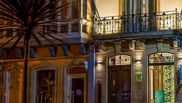 A multi-story building with ornate balconies and a ground-floor shop. - Hotel Boutique Loriente (Ribadeo)