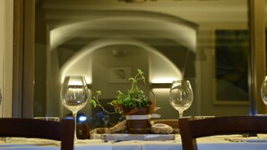 Une table à manger avec deux verres à vin, une plante en pot et une assiette de nourriture.