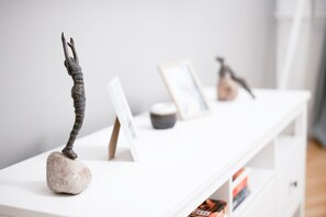 A white console table with decorative sculptures and framed pictures.