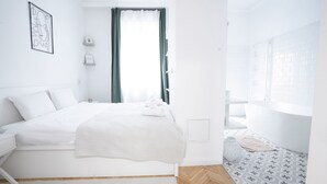 Un dormitorio moderno con una cama bien hecha, una mesita de noche, una ventana con cortinas y un piso con diseño.