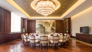 A dining area with a round table set for a meal, surrounded by chairs, with a chandelier above and a painting on the wall. - Jiuhua Mountain Xifeng Hotel (Chizhou)