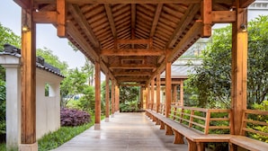 A wooden covered walkway with benches, surrounded by lush greenery. - Jiuhua Mountain Xifeng Hotel (Chizhou)