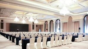 A large conference room with rows of white chairs, black tables, and chandeliers. - Grand New Century Hotel Yixing (Wuxi)