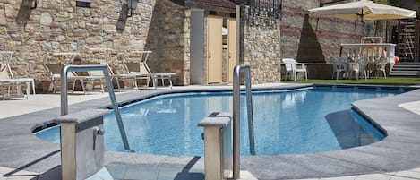 Una piscina al aire libre de temporada, sillones reclinables de piscina