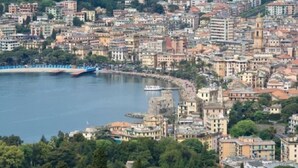A coastal cityscape with dense urban buildings, a waterfront promenade, and a historic tower. - Villa Cristina (Rapallo)