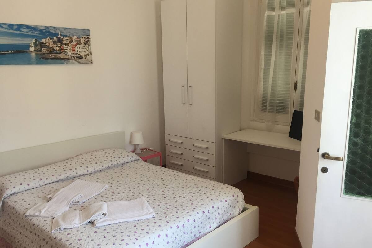 A bedroom with a bed, a desk, and a wardrobe.