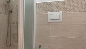 A bathroom with a shower, toilet, bidet, and a toilet paper holder. - Villa Cristina (Rapallo)