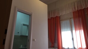 A room with a ceiling fan, a window with orange curtains, and a door leading to another room. - Villa Cristina (Rapallo)