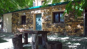 A stone building with a green roof, a wooden bench, and a door. - Casas Rurales Telecabina Las Catifas (Guejar Sierra)