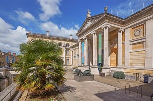 A classical building with columns, a palm tree, and a clear sky.