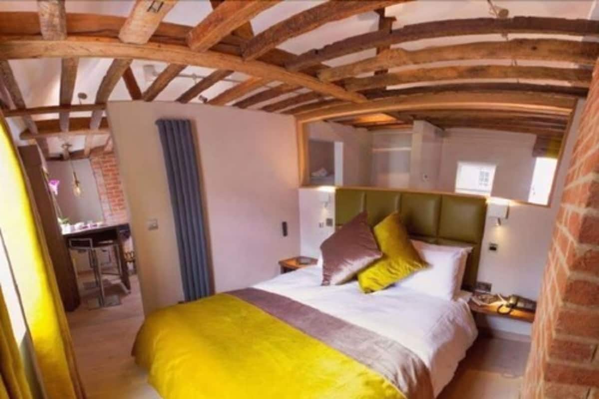 A bedroom with a bed, a headboard, a nightstand, and a window.