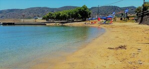 A beach with clear water, a sandy shore, and a few umbrellas.