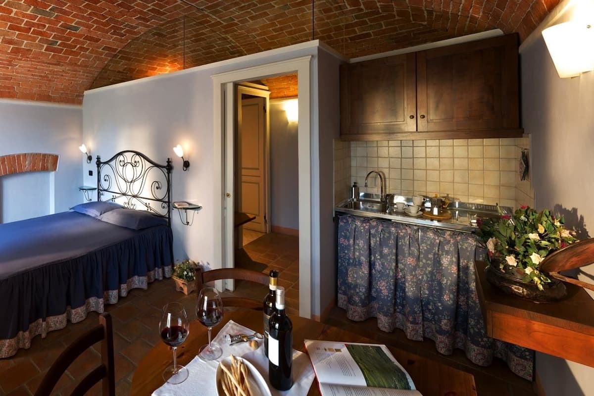 Une pièce de taille modeste comprenant un lit, un bureau, une table à manger et un coin cuisine.