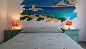 A bedroom with a bed, two bedside tables, and a wall mural depicting a coastal scene. - Lu Lisandru (Arzachena)