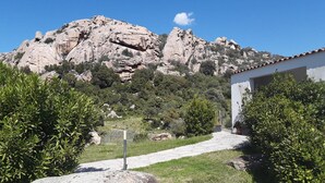 A pathway leading to a building with a mountain backdrop. - Lu Lisandru (Arzachena)