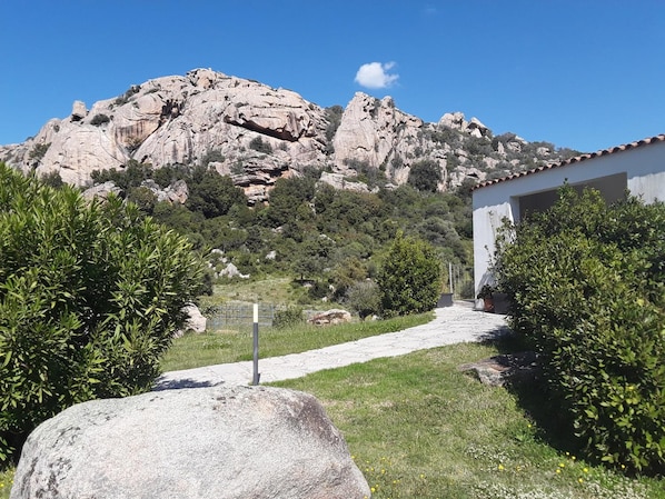 Un sendero que conduce a un edificio con el paisaje de montañas al fondo.
