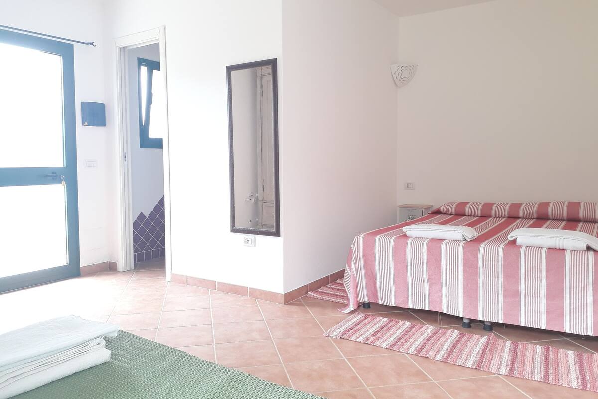 A bedroom with a bed, a mirror, and a green mat.