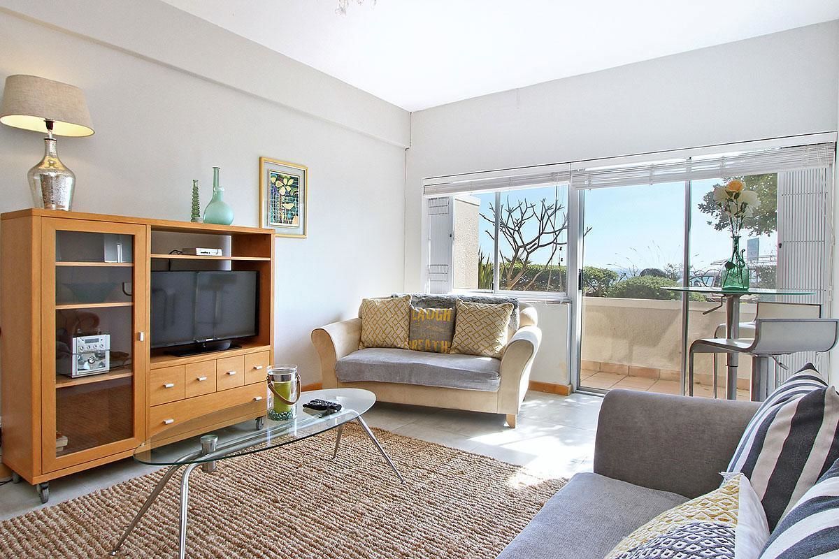 Una sala de estar moderna con televisor, sofá y una mesa de centro de vidrio.