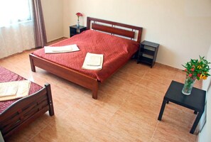 Ein ordentlich eingerichtetes Schlafzimmer mit einem Holzbett, einem Nachttisch mit einer Vase und einem kleinen Tisch mit einem Stuhl.