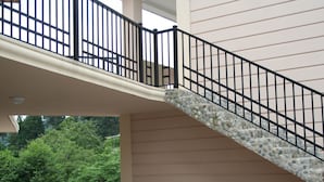 Un espacio al aire libre cubierto con una escalera de piedra, un banco de madera y plantas en macetas.
