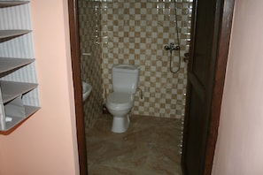 Ein Badezimmer mit Toilette, Dusche und gefliesten Wänden.