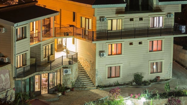 Un edificio de varios pisos con una escalera central, balcones y un patio con plantas.