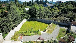 Un patio con césped, un muro de piedra y un pequeño jardín con diversas plantas.