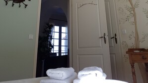 A room with a bed, a chandelier, a door with a tree mural, and a wall-mounted animal decoration. - A L'ombre Du Clocher (Calenzana)