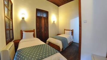 Une chambre avec deux lits, des têtes de lit en bois et des lampes fixées au mur.
