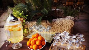Un coin rafraîchissements avec un grand saladier à punch, un bol rempli d’oranges et un plateau de verres à vin.