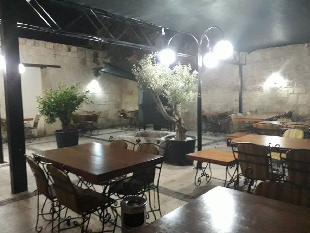 Un restaurante con una decoración rústica, que presenta paredes de ladrillo visto, mobiliario metálico y plantas en macetas.