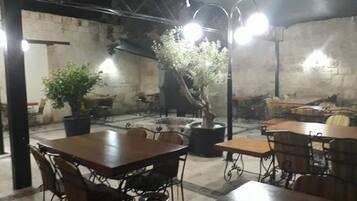 Un restaurante con una decoración rústica, que presenta paredes de ladrillo visto, mobiliario metálico y plantas en macetas.