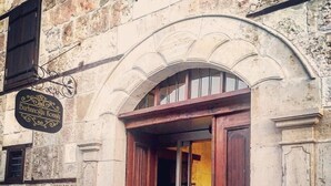 Un bâtiment en pierre avec une porte en bois et une enseigne au-dessus.