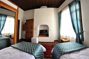 Two single beds with patterned bedding, a wardrobe, and a television are featured in this traditional room.