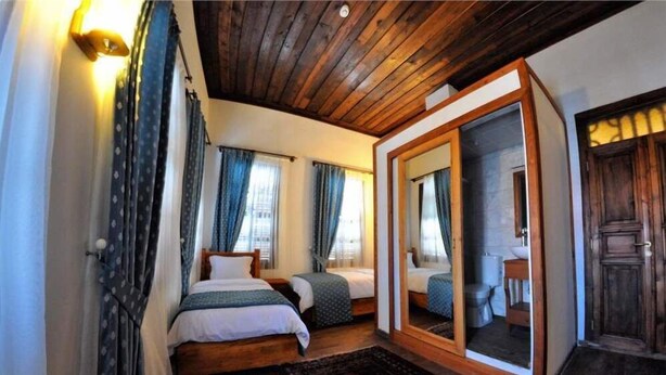 Une chambre avec deux lits, un plafond en bois et un grand miroir.