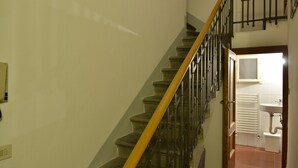 A staircase with a yellow handrail leading to a landing. - Ariete (Florence)