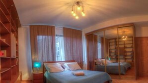 A bedroom with a bed, a wardrobe, a nightstand, and a mirror. - Rais Serviced Apartments (Warsaw)