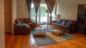 A living room with a sofa set, a coffee table, and a hanging light fixture. - Rais Serviced Apartments (Warsaw)