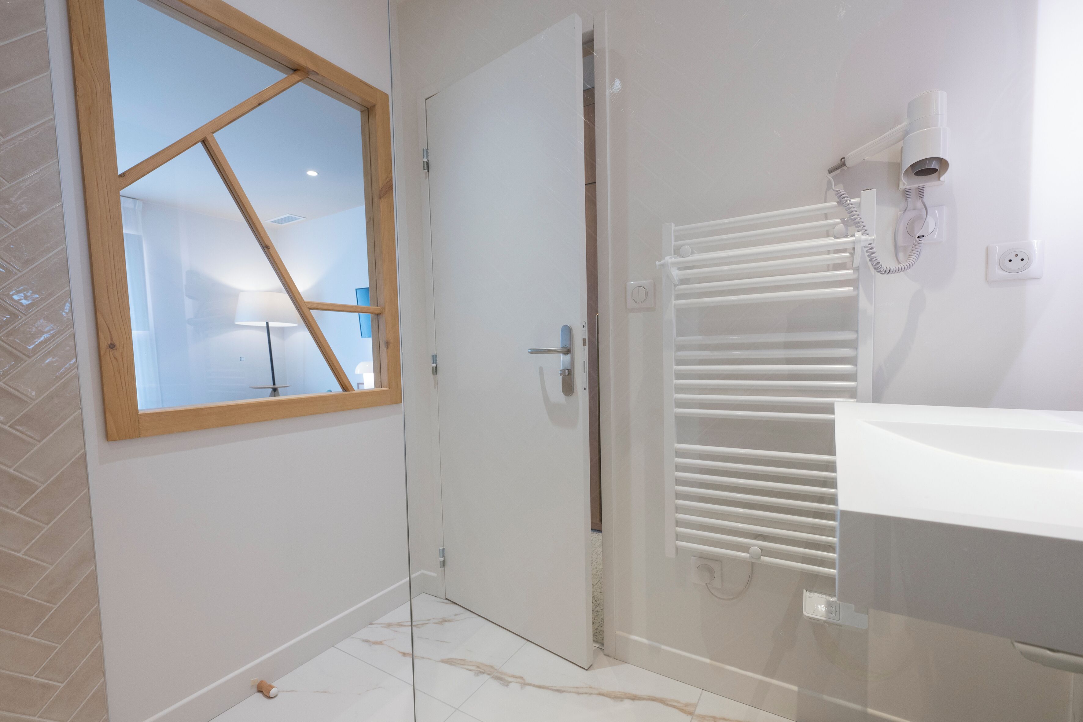 Ein modernes Badezimmer mit einem weißen Waschbecken, einer Duschkabine aus Glas und einem Handtuchhalter.
