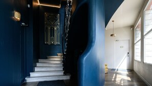 Una escalera moderna con una pared azul oscuro y una obra de arte geométrica en la parte superior.